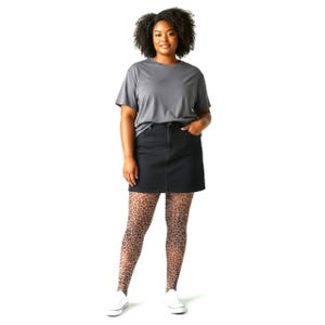 May include: A charcoal gray short-sleeved t-shirt, a black denim mini skirt, and sheer tights featuring a brown and black leopard print pattern, paired with white low-top sneakers. The outfit is worn by a person with dark curly hair.