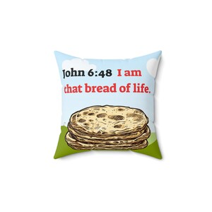 Puede incluir: Una almohada blanca con un fondo azul y verde. La almohada tiene un dibujo de una pila de pan plano y el texto "Juan 6:48 Yo soy el pan de vida."