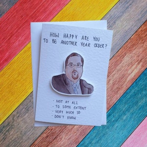 Peut inclure: Une carte blanche avec une illustration aquarelle d'un homme barbu portant des lunettes. La carte dit "How happy are you to be another year older?" et propose un choix de réponses avec les options "Not at all", "To some extent", "Very much so", et "Don't know".
