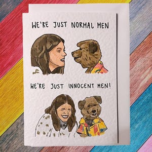 Op de afbeelding: Een kaart met een handgetekende illustratie van twee mensen en twee honden. De tekst op de kaart luidt "We're just normal men. We're just innocent men!"