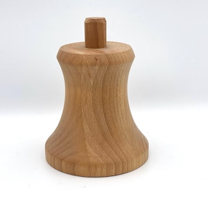 May include: A turned wooden object with a light brown finish. The piece has a rounded base, a flared midsection, and a small, cylindrical top. The wood grain is visible throughout the piece, which appears to be a decorative or functional item.