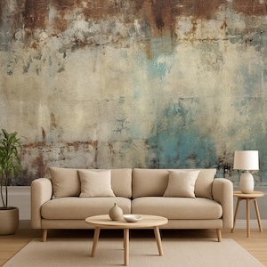 Op de afbeelding: Een woonkamer met een beige bank, kussens en een ronde houten salontafel. De getextureerde muur heeft bruine, blauwe en beige tinten. Een plantenpot en een lamp zijn ook zichtbaar.