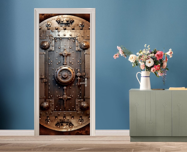 May include: A close-up of a metal door with a large, circular lock in the center. The door is made of thick metal and has a weathered, industrial look. The door is surrounded by a white frame.