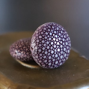 Peut inclure: Deux perles rondes de couleur violet et blanc avec une surface texturée.