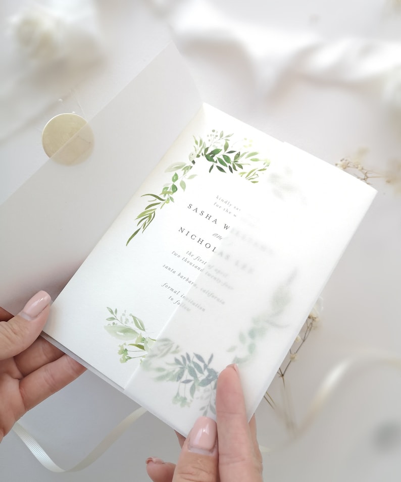 Puede incluir: Una invitaci&oacute;n de boda blanca con un dise&ntilde;o floral verde. La invitaci&oacute;n dice "Por favor, responde a la invitaci&oacute;n para la boda de Sasha W y Nicholas el primero de noviembre de dos mil Santa Barbara, California invitaci&oacute;n formal a seguir."