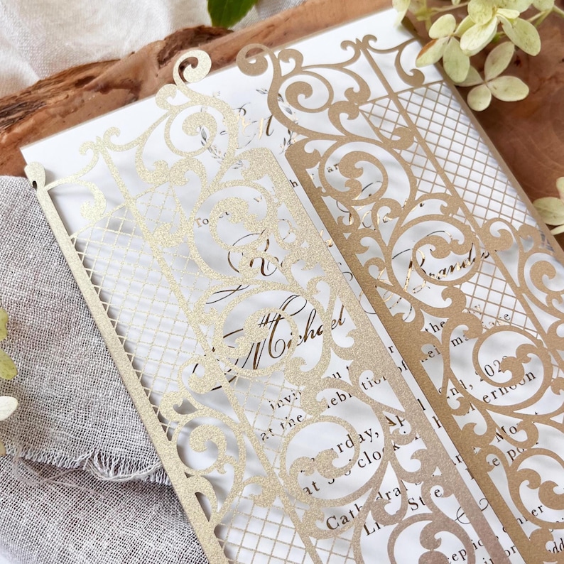 May include: Elegant gold laser-cut wedding invitation with intricate floral and lattice designs. The invitation features the names "Michael" and "Rachel" and event details. The design includes decorative borders and a classic, formal style.