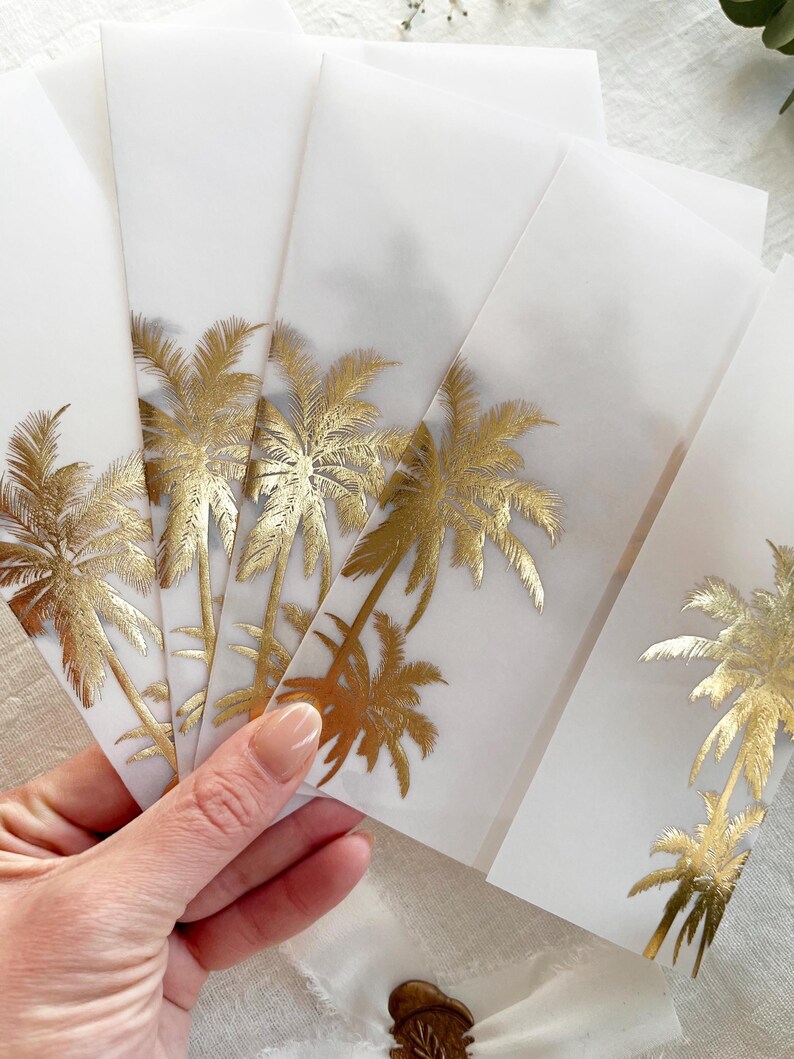 Peut inclure: Plusieurs enveloppes blanches orn&eacute;es de motifs de palmiers dor&eacute;s. Les enveloppes sont tenues, r&eacute;v&eacute;lant les d&eacute;tails dor&eacute;s. Chaque enveloppe pr&eacute;sente le m&ecirc;me motif, cr&eacute;ant un th&egrave;me tropical coh&eacute;rent.