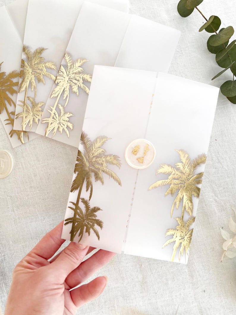 Peut inclure: Enveloppes blanches translucides avec des motifs de palmiers dor&eacute;s. Les enveloppes sont scell&eacute;es avec un sceau de cire rose clair. Plusieurs enveloppes sont visibles, dont une tenue &agrave; la main.