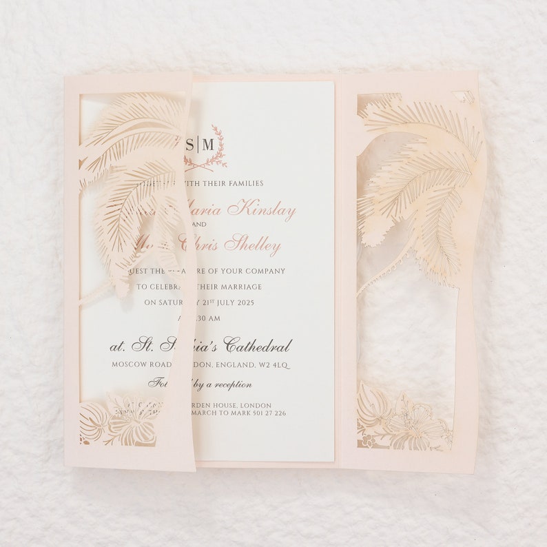 May include: A light pink wedding invitation with a laser-cut palm tree design. The invitation is tri-fold, with the text "Maria Kinslay and Chris Shelley" and wedding details printed inside. The invitation includes the date, time, and location of the wedding.