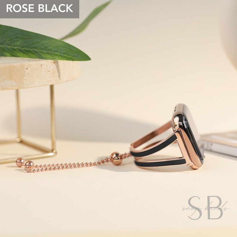 May include: Rose gold and black Apple Watch band with a chain detail. The band is made of metal and has a sleek, modern design.