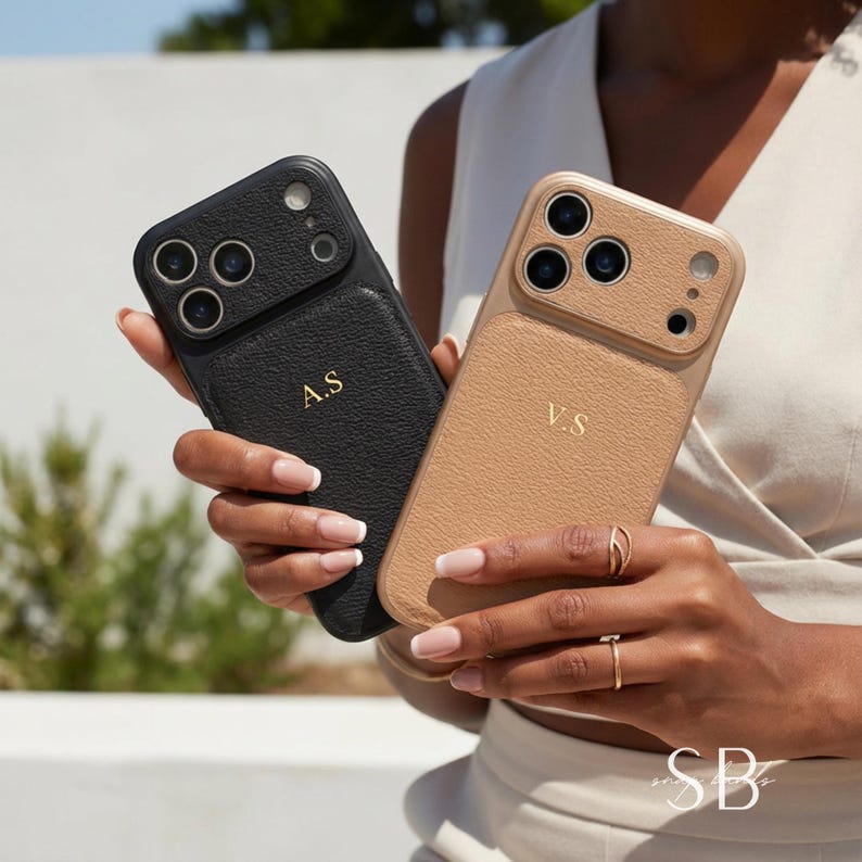 May include: Two personalized phone cases, one black and one tan, are held up. The black case has the initials "A.S" in gold, while the tan case has "V.S". Both cases have a textured leather appearance and a camera module.