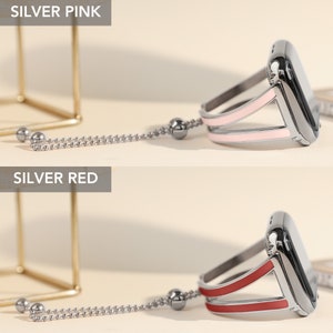 May include: Two silver Apple Watch bands with a chain and a charm. The band on the top is pink and the band on the bottom is red.