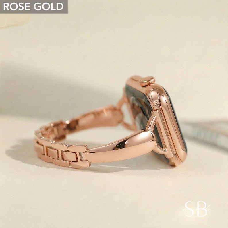 May include: Rose gold smartwatch with a matching link band. The watch face is black, and the band is made of small, rectangular links. The watch is angled, showing the side and the band's connection to the watch face. The text "ROSE GOLD" is in the top left corner.