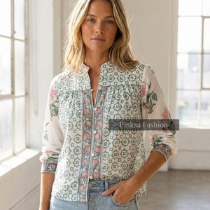 Könnte beinhalten: Weißes Hemd mit floralem und geometrischem Muster in Rosa und Grün. Das Hemd hat lange Ärmel und einen Stehkragen. Der Text "Pinksa Fashion" ist auf dem Hemd zu sehen.