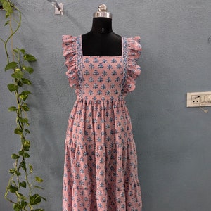 May include: A pink tiered maxi dress with a square neckline and blue floral print. The dress has ruffle straps and a gathered skirt.