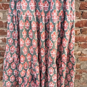 May include: A tiered maxi skirt with a floral print in shades of green, pink, and white. The skirt has a relaxed fit and a flowy silhouette.