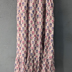 May include: A white tiered maxi dress with a pink and blue floral print. The dress has a fitted bodice and a flowy skirt.
