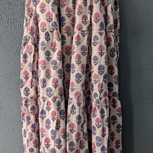 May include: A white maxi skirt with a floral print in shades of pink and blue. The skirt has multiple tiers and a flowy silhouette.