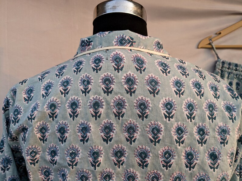May include: A light blue shirt with a white and blue floral pattern. The shirt has a collar and a button-up front.
