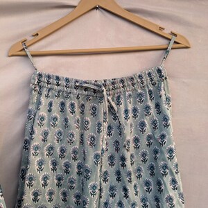 May include: A pair of light blue pajama pants with a white and blue floral print. The pants have an elastic waistband and a drawstring.