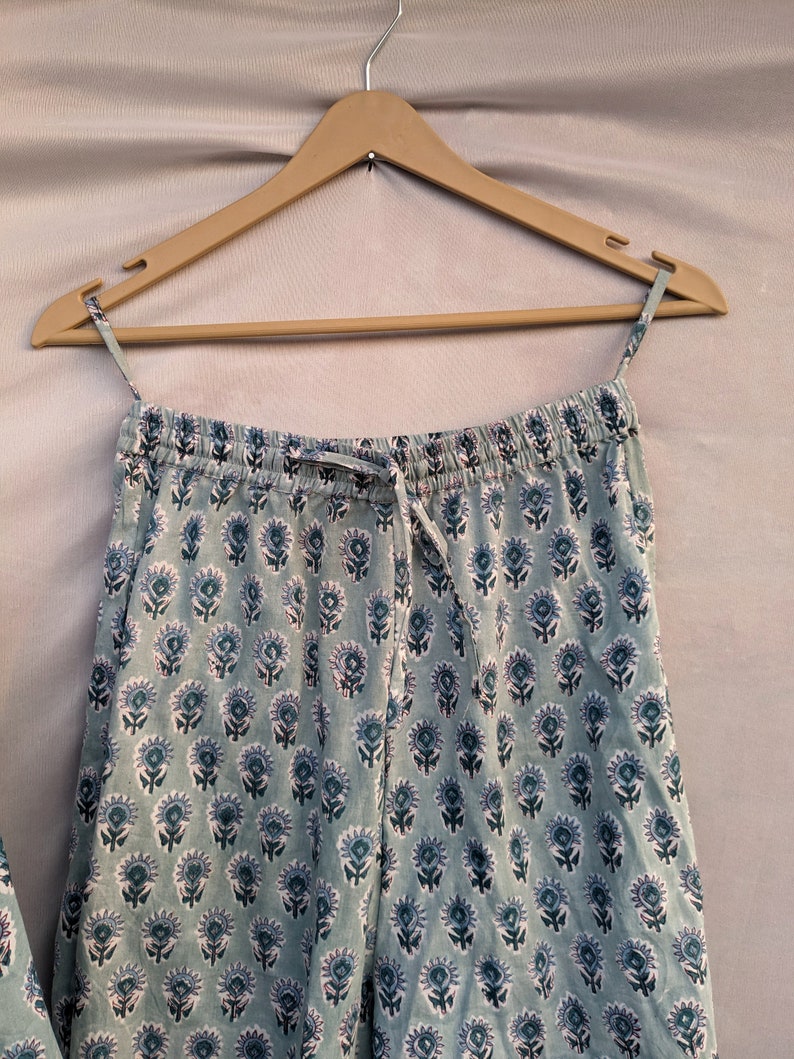 May include: A pair of light blue pajama pants with a white and blue floral print. The pants have an elastic waistband and a drawstring.