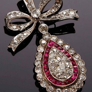 May include: A silver pendant with a diamond-encrusted bow and a teardrop-shaped pendant with a ruby and diamond halo.