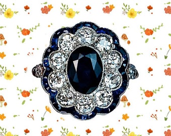 May include: A vintage-style ring with a large oval blue sapphire surrounded by smaller diamonds and blue sapphires. The ring is set in silver.