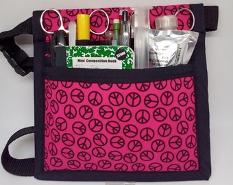 Può includere: Una cintura utility in tessuto rosa con bordatura nera e un motivo a segno di pace. La cintura ha una varietà di tasche e passanti per trasportare strumenti e forniture. La cintura è anche dotata di una cinghia rimovibile.