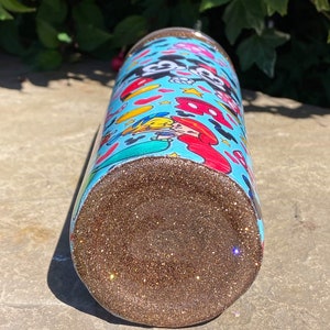 May include: A blue and white tumbler with a glitter bottom. The tumbler features a cartoon design of Mickey Mouse and Minnie Mouse.