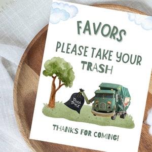 K&ouml;nnte beinhalten: Ein wei&szlig;es Schild mit den Worten "FAVORS PLEASE TAKE YOUR TRASH THANKS FOR COMING!" in Gr&uuml;n. Das Schild zeigt einen Cartoon-M&uuml;llwagen, einen Baum, einen M&uuml;llsack und Wolken. Das Schild befindet sich auf einem Holztablett.