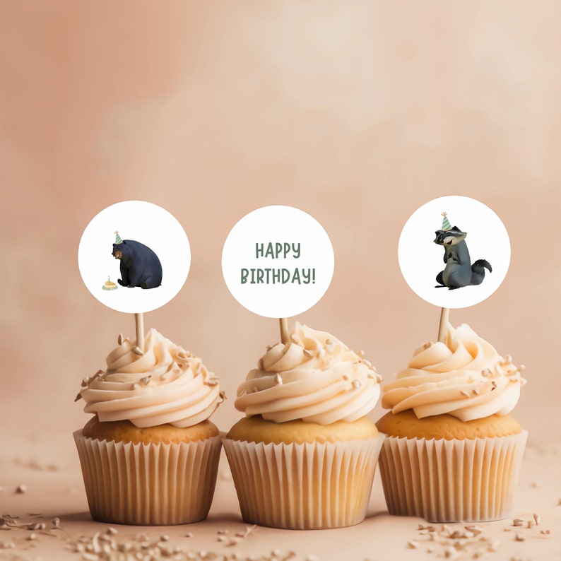 K&ouml;nnte beinhalten: Drei Cupcakes, die mit runden Toppern verziert sind, die einen B&auml;ren, einen Waschb&auml;ren und den Text "Happy Birthday!" zeigen. Die Topper sind wei&szlig; mit gr&uuml;nen Akzenten.