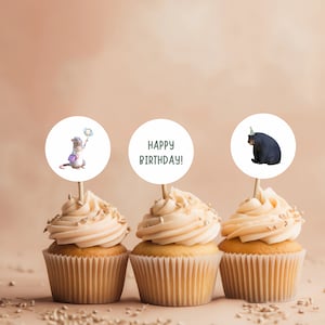 K&ouml;nnte beinhalten: Drei Cupcakes mit wei&szlig;em Frosting und Streuseln. Jeder Cupcake hat einen runden Topper mit einem anderen Design. Ein Topper zeigt eine Comic-Ratte, die einen Zauberstab h&auml;lt, ein anderer sagt "Happy Birthday!" und der letzte zeigt einen Comic-B&auml;ren, der eine Partym&uuml;tze tr&auml;gt.