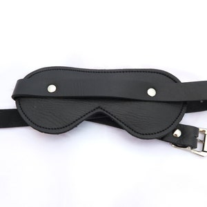 Puede incluir: Antifaz de cuero negro con correa ajustable y hebilla plateada.