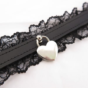 May include: Black choker necklace with a heart-shaped lock pendant. The choker is made of black leather and lace.