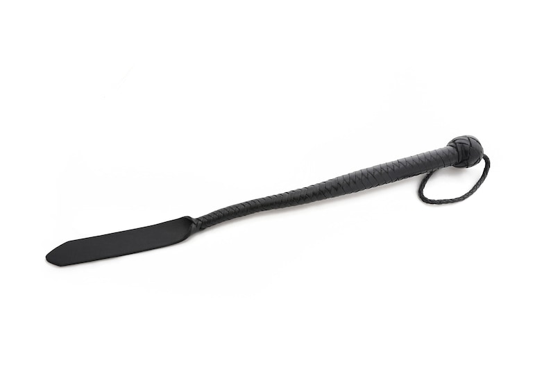 May include: A black leather paddle with a braided handle and a loop at the end.