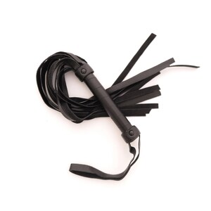 May include: A black leather flogger featuring a cylindrical handle wrapped in smooth leather, secured with two circular rivets at the top and bottom. Multiple long, flat leather strips extend from the handle, with a wrist loop attached at the base.
