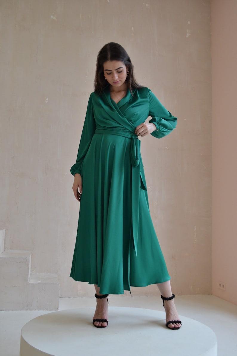 May include: A long-sleeved emerald green wrap dress with a V-neckline and a tie at the waist.