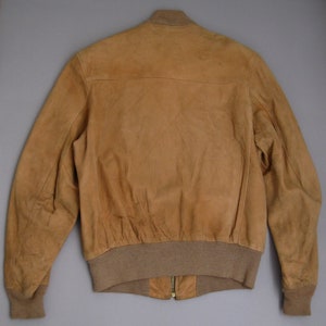 K&ouml;nnte beinhalten: Eine braune Lederbomberjacke mit geripptem Strickkragen, B&uuml;ndchen und Bund. Die Jacke hat einen Rei&szlig;verschluss und einen goldenen Rei&szlig;verschluss-Zipper.