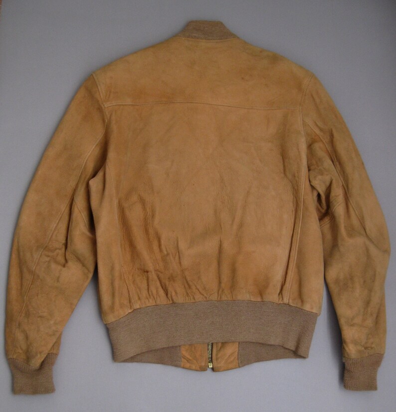 K&ouml;nnte beinhalten: Eine braune Lederbomberjacke mit geripptem Strickkragen, B&uuml;ndchen und Bund. Die Jacke hat einen Rei&szlig;verschluss und einen goldenen Rei&szlig;verschluss-Zipper.
