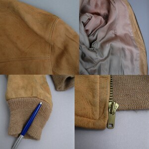 K&ouml;nnte beinhalten: Eine braune Wildlederbomberjacke mit Rei&szlig;verschluss und gerippten Strickb&uuml;ndchen und Kragen. Die Jacke hat ein braunes Satinfutter.