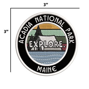 Może przedstawiać: Okrągła naszywka haftowana o średnicy 7,6 cm z białym obramowaniem, czarnym tłem i białym tekstem, kt&oacute;ry brzmi "Acadia National Park, Maine". Środek naszywki przedstawia retro scenę zachodu słońca z namiotem i słowem "Explore" w białym k&oacute;łku.