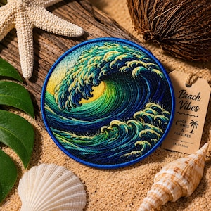 May include: A round embroidered patch featuring a stylized ocean wave in shades of blue, green, and yellow. The patch is surrounded by a blue border. The image includes a starfish, seashells, and a tag that says "Beach Vibes".