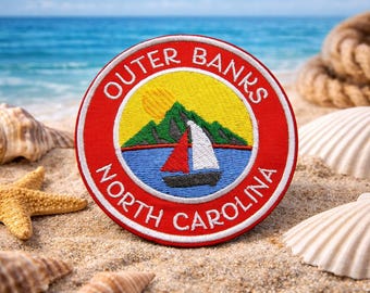 May include: Embroidered patch with a red border and the words "Outer Banks North Carolina" in white. The patch features a sailboat on blue water, a yellow sun, and green mountains. Seashells and a starfish are in the sand.