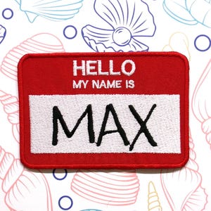 May include: Red felt name tag with white border and white text that reads "HELLO MY NAME IS MAX".