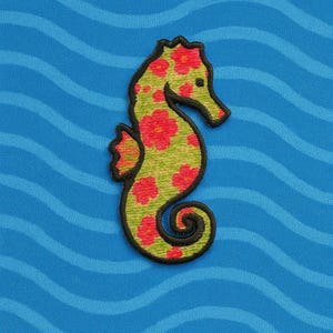May include: Embroidered seahorse patch with a green body, red floral accents, and a black outline. The patch is set against a blue background with wavy lines, creating a nautical theme. The seahorse is a whimsical design.