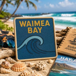 May include: A square blue sign with a light-coloured border featuring the yellow text WAIMEA BAY above a stylised light blue ocean wave graphic. The sign is positioned among various seashells, a surf journal, and sunglasses on a sandy beach.