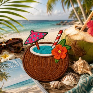 May include: A circular embroidered patch featuring a brown coconut shell filled with blue liquid, topped with a pink polka-dot cocktail umbrella, a red and white striped straw, and an orange hibiscus flower with green leaves.