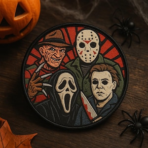 May include: Round patch featuring four horror movie characters: Freddy Krueger, Jason Voorhees, Michael Myers, and Ghostface. The patch has a black border and a red and orange background. Halloween-themed.
