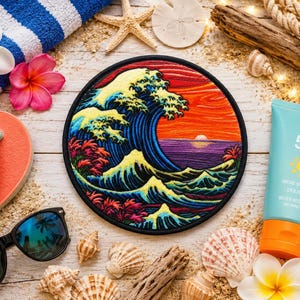 May include: A circular embroidered patch featuring a stylised ocean wave in shades of blue, yellow, and red against a sunset background. The design includes intricate stitching details of cresting waves and a vibrant orange and purple horizon.