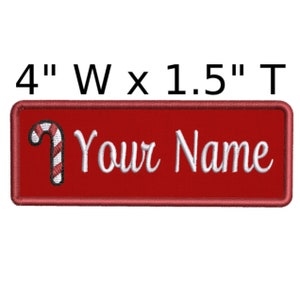 May include: Red rectangular iron-on patch with a white candy cane and the text "Your Name" in white cursive font. The patch measures 4 inches wide by 1.5 inches tall.